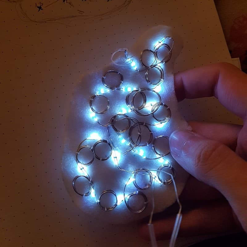 a coiled-up wire of 20 LED lights sewn onto a vaguely wing-shaped piece of felt