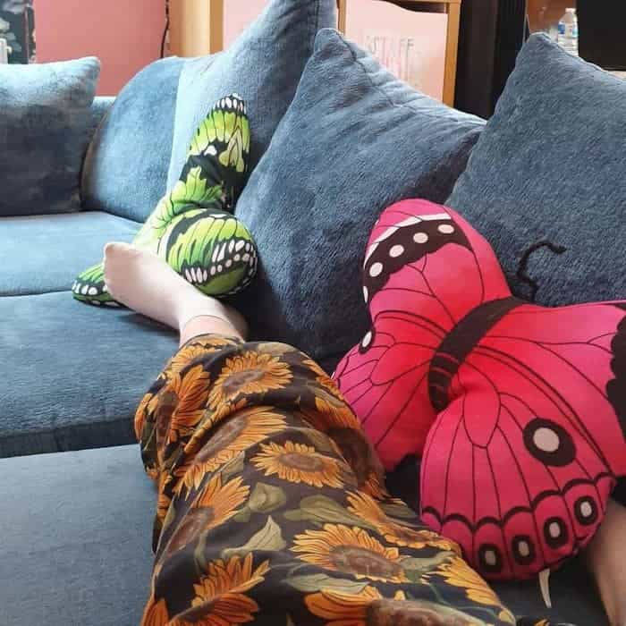 my stretched-out leg and a couple of butterfly cushions alongside regular cushions, on a hostel sofa