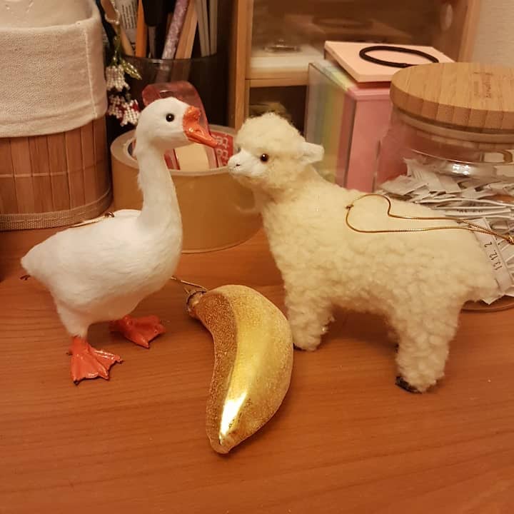 ornaments of goose and sheep standing on my table, with glass banana ornament strewn between them