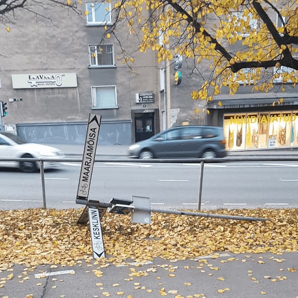 a city district signpost bent entirely to its side, propped in a way where one sign points up
