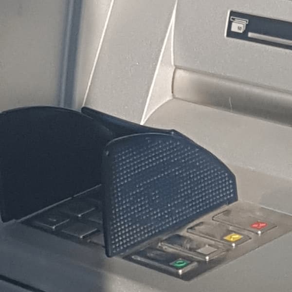 a simplified eye on the side of the privacy cover of an ATM's PIN-code pad