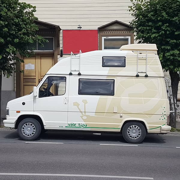 a parked white camper van with beige snail design taking up most of its side, with green detailing on the bottom