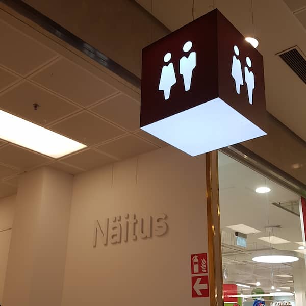 large hanging cube signage for toilets leading to a hallway with some estonian signage